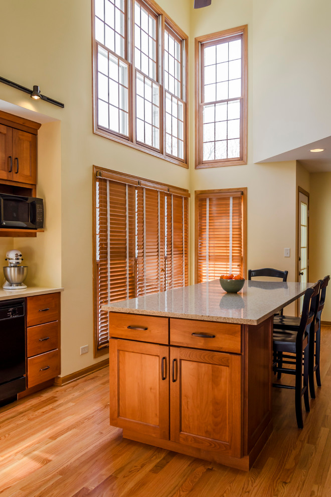 Eat-in kitchen - large transitional l-shaped light wood floor eat-in kitchen idea in Chicago with an undermount sink, recessed-panel cabinets, medium tone wood cabinets, quartz countertops, black appliances and an island