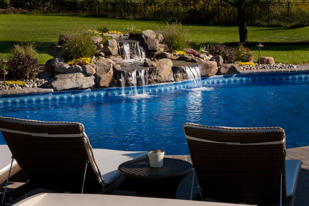Inspiration for a large modern backyard custom-shaped lap pool in Philadelphia with a water feature and natural stone pavers.