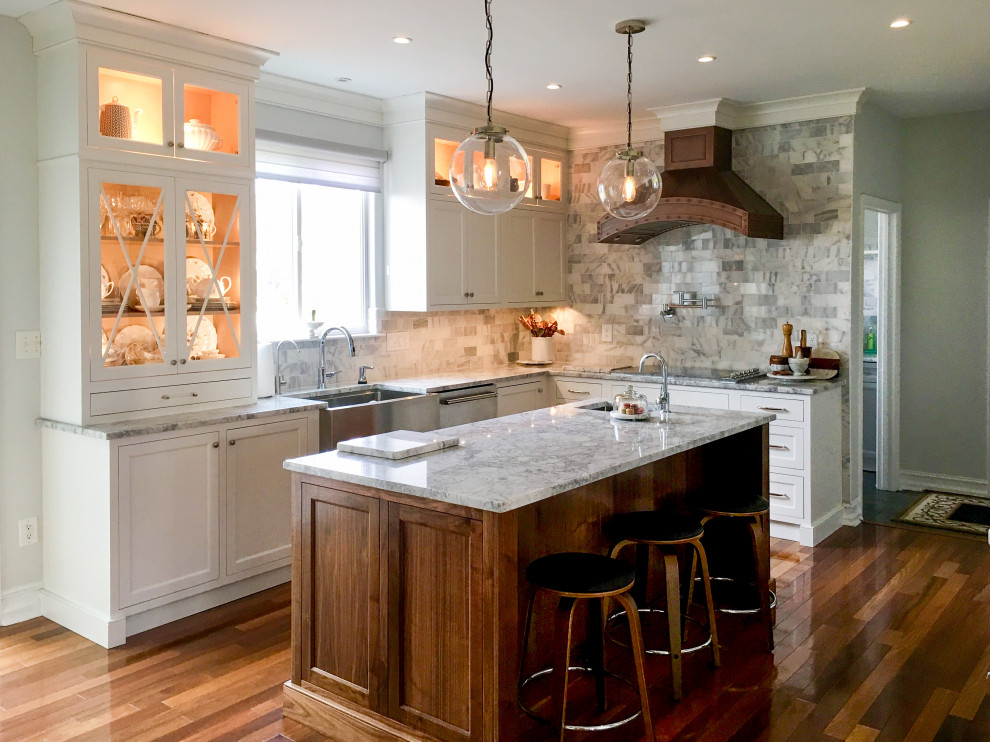 Inspiration for a mid-sized country l-shaped eat-in kitchen in Newark with a farmhouse sink, shaker cabinets, white cabinets, granite benchtops, grey splashback, stainless steel appliances, medium hardwood floors, with island, brown floor and grey benchtop.