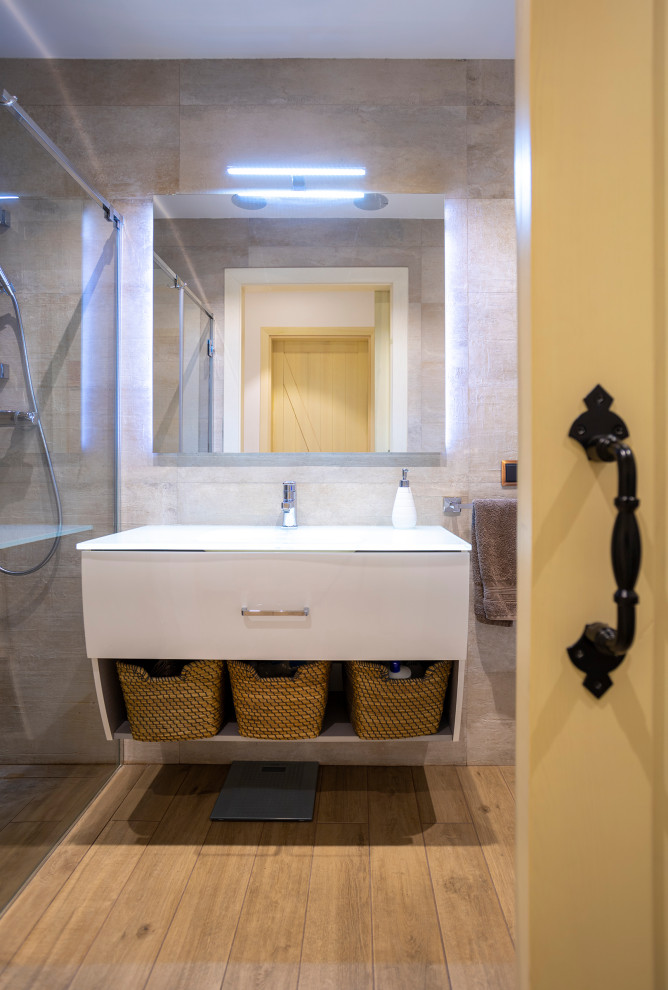 Inspiration for a medium sized contemporary ensuite bathroom in Barcelona with freestanding cabinets, white cabinets, a built-in shower, a wall mounted toilet, beige tiles, porcelain flooring, an integrated sink, brown floors, a hinged door, white worktops, an enclosed toilet, a single sink and a floating vanity unit.