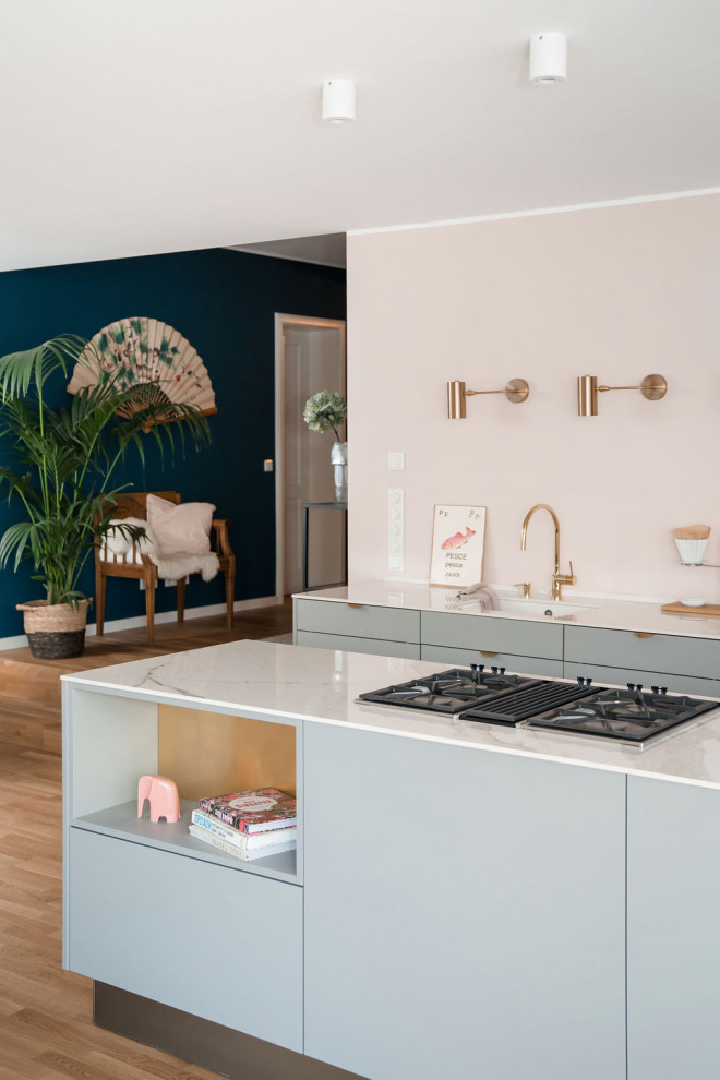 Design ideas for a mid-sized scandinavian galley eat-in kitchen in Other with an undermount sink, flat-panel cabinets, grey cabinets, pink splashback, black appliances, light hardwood floors, with island and white benchtop.