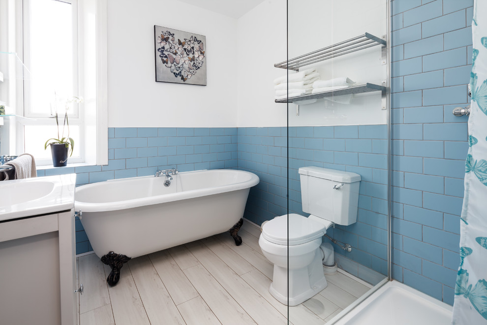 This is an example of a mid-sized beach style master bathroom in Manchester with a claw-foot tub, a corner shower, a one-piece toilet, blue tile, subway tile, beige cabinets, white walls, a console sink, beige floor and an open shower.