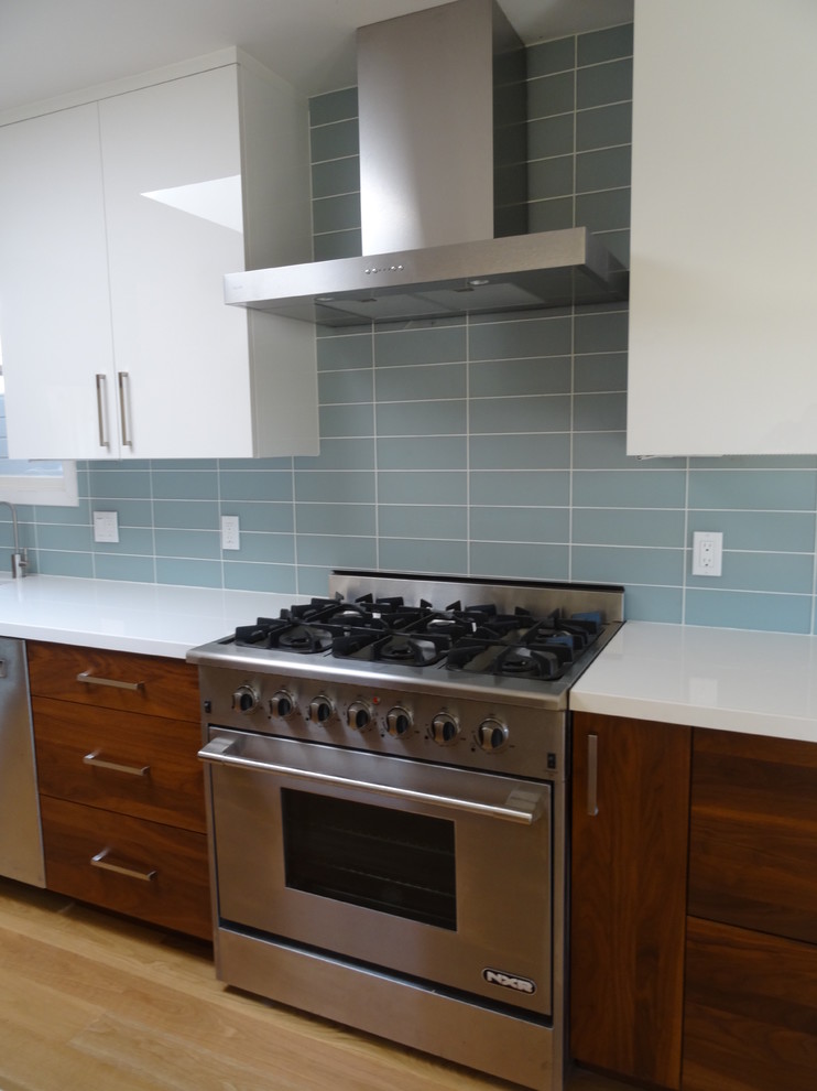 Large modern single-wall eat-in kitchen in San Francisco with a single-bowl sink, flat-panel cabinets, dark wood cabinets, granite benchtops, blue splashback, glass tile splashback, stainless steel appliances, light hardwood floors and with island.