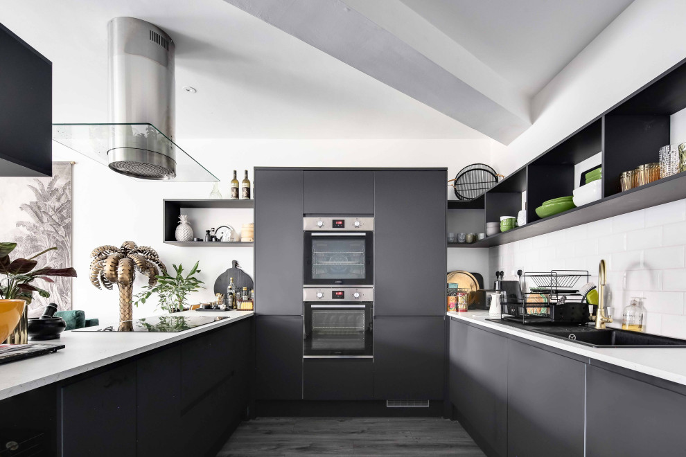 Inspiration for a medium sized contemporary grey and white u-shaped open plan kitchen in London with a double-bowl sink, flat-panel cabinets, grey cabinets, composite countertops, white splashback, metro tiled splashback, integrated appliances and white worktops.