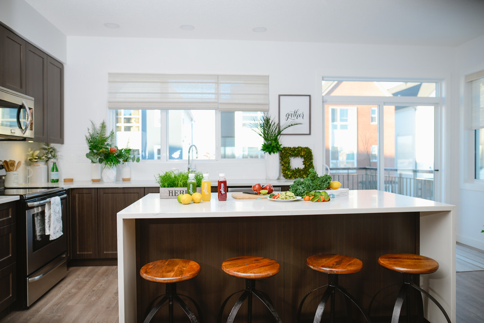 Mid-sized transitional l-shaped medium tone wood floor open concept kitchen photo in Calgary with an undermount sink, recessed-panel cabinets, dark wood cabinets, stainless steel appliances and an island