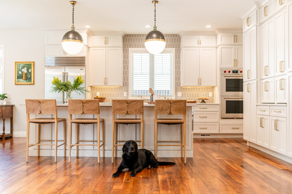 Open concept kitchen - large transitional l-shaped dark wood floor and brown floor open concept kitchen idea in Denver with a farmhouse sink, shaker cabinets, beige cabinets, quartz countertops, beige backsplash, ceramic backsplash, stainless steel appliances, an island and white countertops