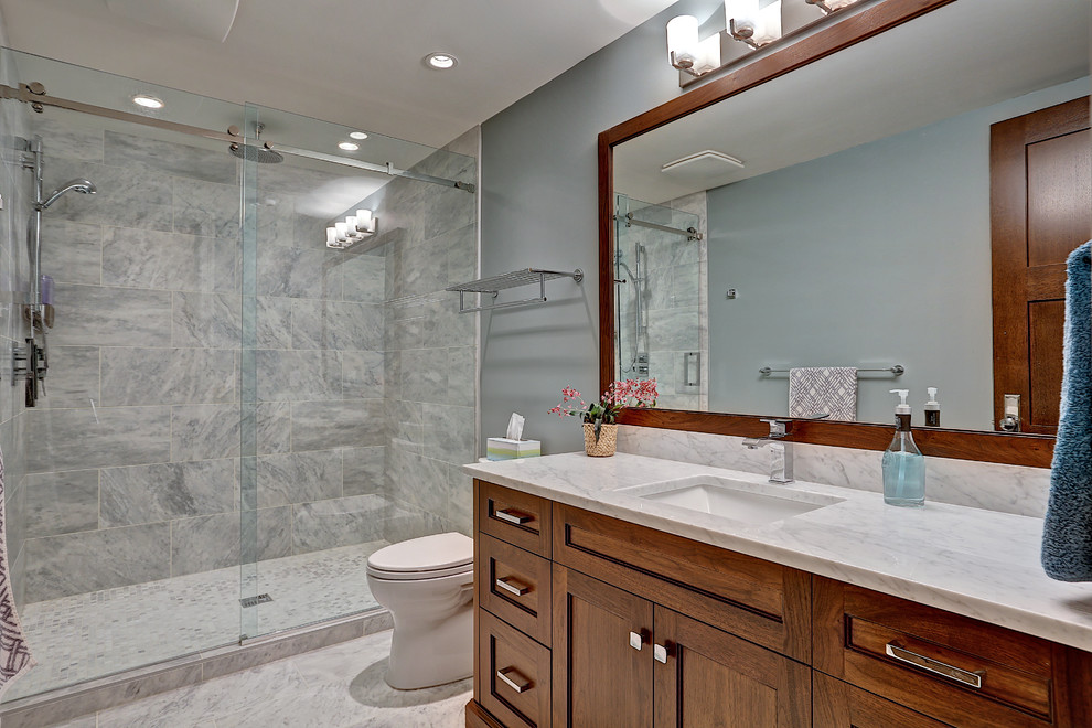 This is an example of a mid-sized transitional 3/4 bathroom in Calgary with shaker cabinets, dark wood cabinets, an alcove shower, a one-piece toilet, white tile, stone tile, grey walls, marble floors, an undermount sink and marble benchtops.