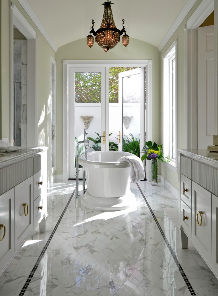 Photo of a transitional bathroom in New York with a freestanding tub, recessed-panel cabinets, white cabinets, mosaic tile, marble floors and white tile.