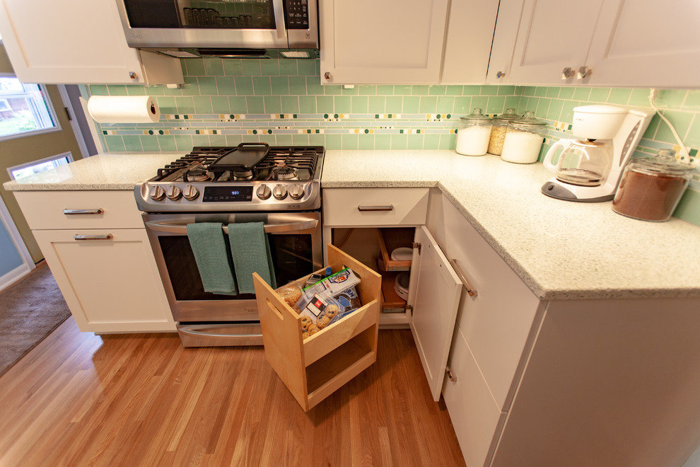 Photo of a midcentury separate kitchen in Minneapolis with an undermount sink, shaker cabinets, white cabinets, recycled glass benchtops, green splashback, mosaic tile splashback, stainless steel appliances, medium hardwood floors, no island, brown floor and white benchtop.