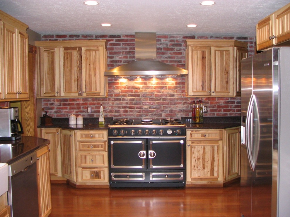 Example of a mid-sized mountain style single-wall medium tone wood floor eat-in kitchen design in Chicago with shaker cabinets, distressed cabinets, quartz countertops, brown backsplash, brick backsplash, stainless steel appliances and no island