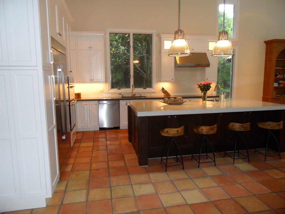 Eat-in kitchen - large transitional l-shaped eat-in kitchen idea in Miami with an undermount sink, shaker cabinets, white cabinets, quartz countertops, white backsplash, ceramic backsplash, stainless steel appliances and an island