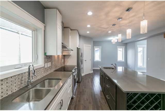 Inspiration for a mid-sized transitional l-shaped vinyl floor open concept kitchen remodel in Edmonton with an undermount sink, multicolored backsplash, stainless steel appliances, an island, shaker cabinets, white cabinets, concrete countertops and mosaic tile backsplash