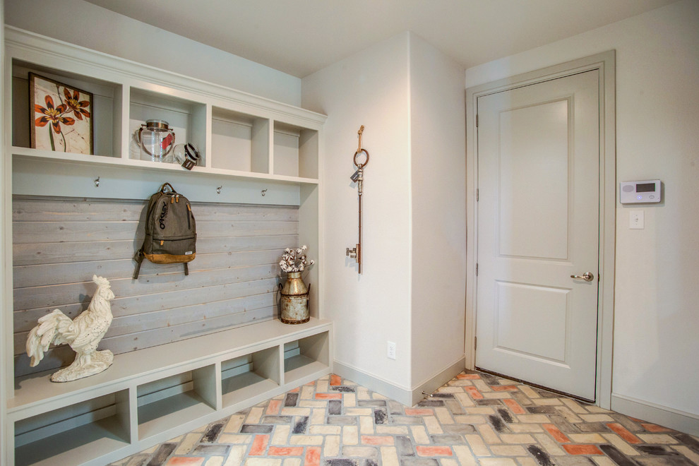 Inspiration for a country mudroom in Austin with white walls, brick floors, a single front door and a gray front door.