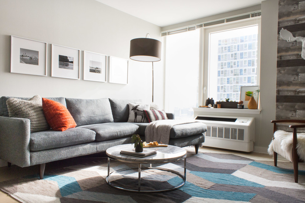 Example of a small minimalist enclosed light wood floor and beige floor living room design in New York with gray walls, no fireplace and a tv stand