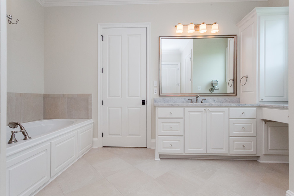 Mid-sized elegant master white tile and ceramic tile ceramic tile alcove bathtub photo in New Orleans with raised-panel cabinets, white cabinets, beige walls, a drop-in sink and marble countertops