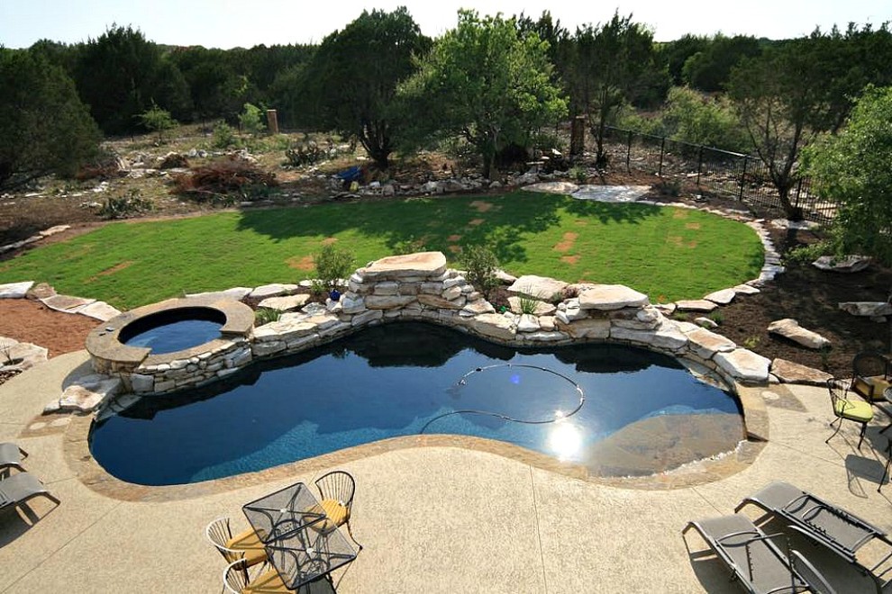 Inspiration for a mid-sized tropical backyard custom-shaped lap pool in Austin with a hot tub and concrete slab.