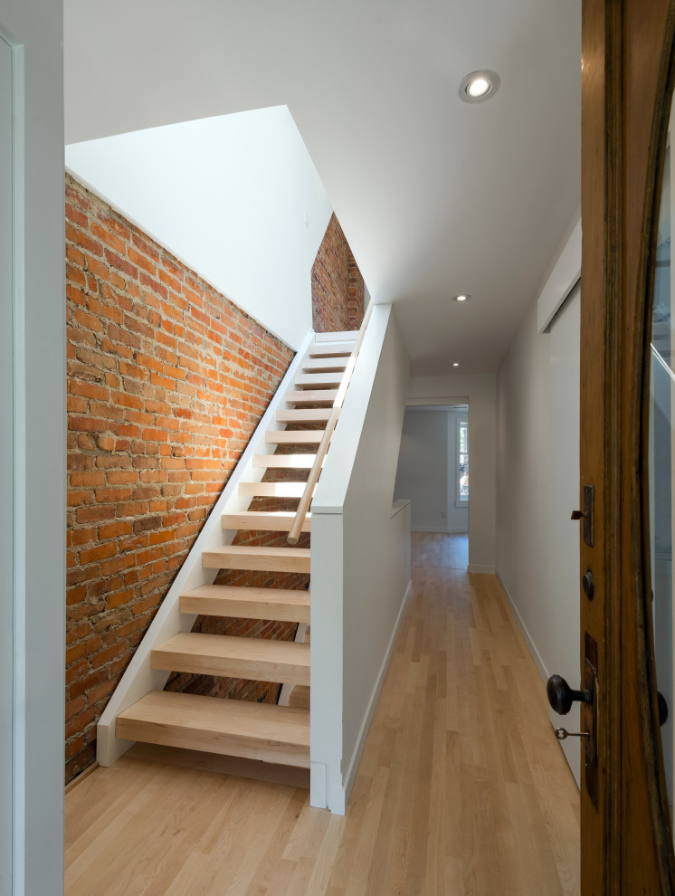Design ideas for a modern wood straight staircase in Toronto with open risers, wood railing and brick walls.