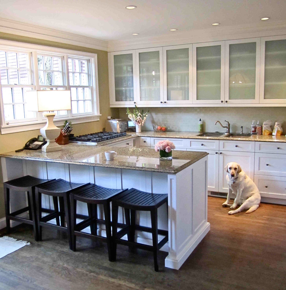 Inspiration for a large traditional u-shaped kitchen in Chicago with a double-bowl sink, shaker cabinets, white cabinets, granite benchtops, beige splashback, stone tile splashback, panelled appliances, dark hardwood floors, a peninsula and brown floor.