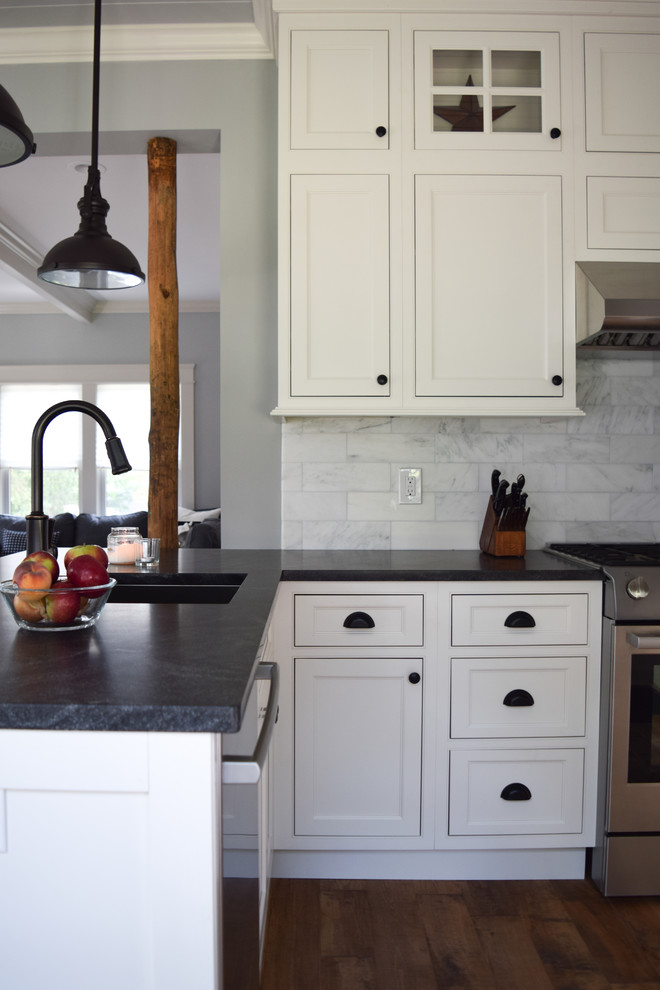 This is an example of a small country u-shaped eat-in kitchen in New York with an undermount sink, beaded inset cabinets, white cabinets, soapstone benchtops, marble splashback, stainless steel appliances, medium hardwood floors and a peninsula.