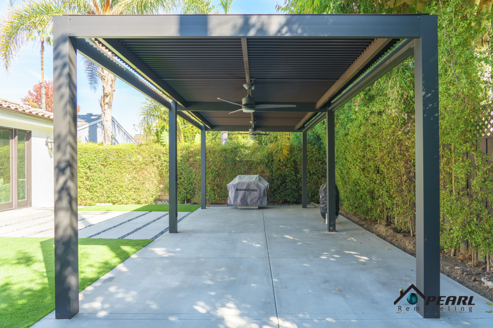 Immagine di un patio o portico minimalista di medie dimensioni e dietro casa con un caminetto, lastre di cemento e una pergola