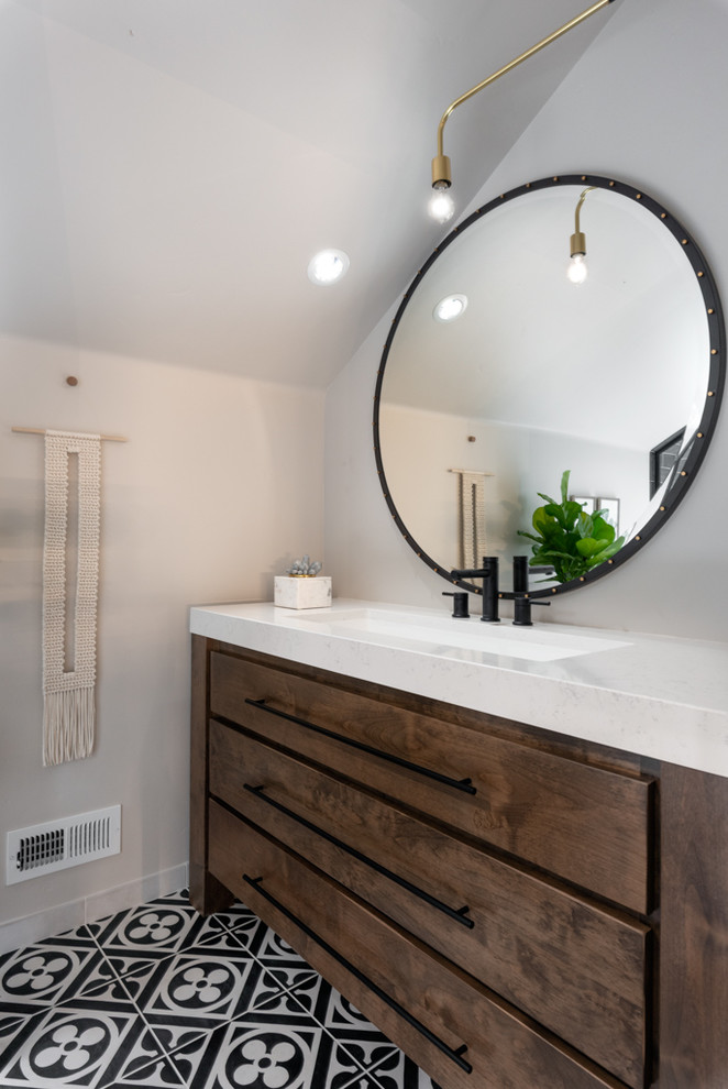 Small eclectic bathroom in Boise with furniture-like cabinets, brown cabinets, black tile, porcelain tile, grey walls, porcelain floors, a trough sink, engineered quartz benchtops, multi-coloured floor, a hinged shower door and white benchtops.