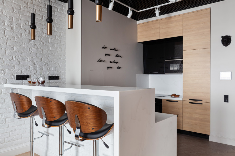This is an example of a mid-sized industrial galley eat-in kitchen in Moscow with an undermount sink, flat-panel cabinets, medium wood cabinets, solid surface benchtops, white splashback, black appliances, ceramic floors, with island, grey floor and white benchtop.