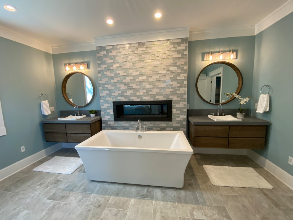 This is an example of a large transitional master bathroom in Milwaukee with flat-panel cabinets, dark wood cabinets, a freestanding tub, blue walls, light hardwood floors, a drop-in sink, engineered quartz benchtops, beige floor, grey benchtops, a double vanity and a floating vanity.