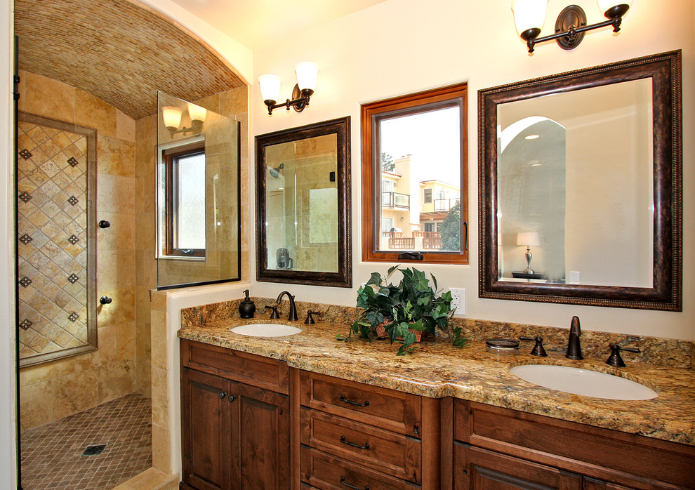 Photo of a mid-sized traditional master bathroom in San Diego with recessed-panel cabinets, medium wood cabinets, a two-piece toilet, beige tile, brown tile, stone slab, beige walls, an undermount sink, granite benchtops, an open shower, a corner shower, ceramic floors and brown floor.