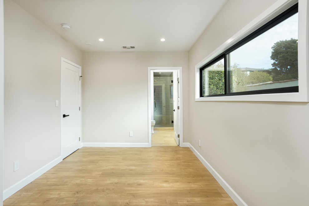 Exemple d'une chambre parentale chic de taille moyenne avec un mur blanc, sol en stratifié et un sol marron.