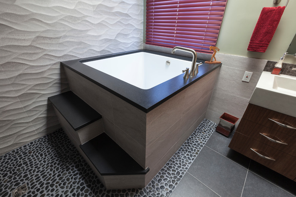 Mid-sized contemporary master bathroom in Bridgeport with flat-panel cabinets, medium wood cabinets, concrete benchtops, a japanese tub, a curbless shower, a two-piece toilet, black tile, porcelain tile, grey walls and porcelain floors.