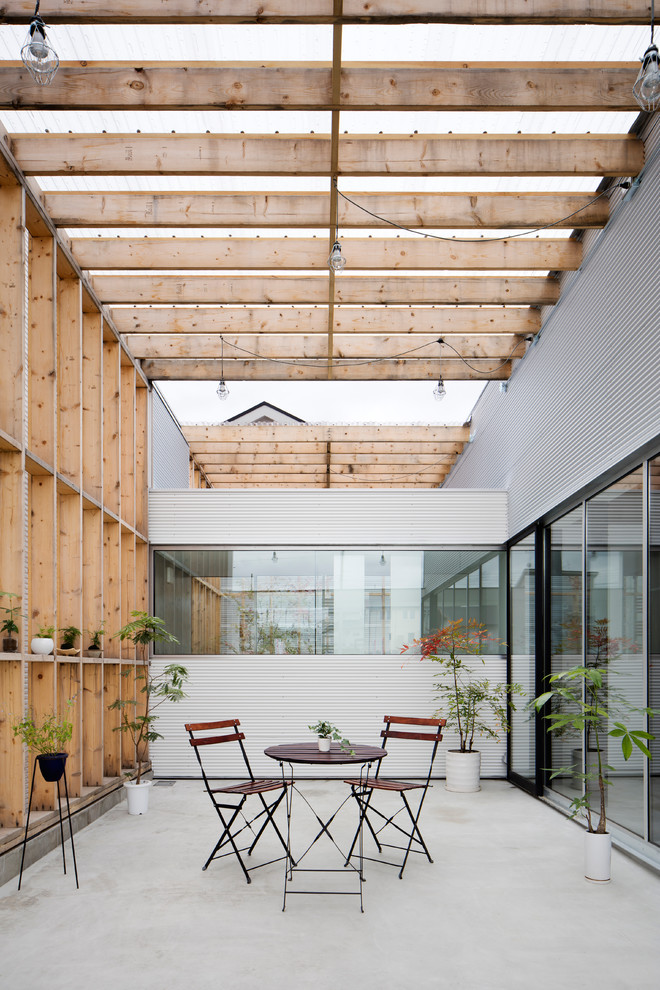 Industrial courtyard patio in Kyoto with concrete pavers and a pergola.