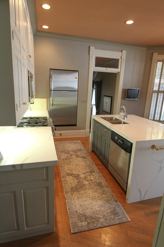 Kitchen - transitional medium tone wood floor and brown floor kitchen idea with an undermount sink, raised-panel cabinets, white cabinets, quartz countertops, white backsplash, ceramic backsplash, stainless steel appliances, an island and white countertops