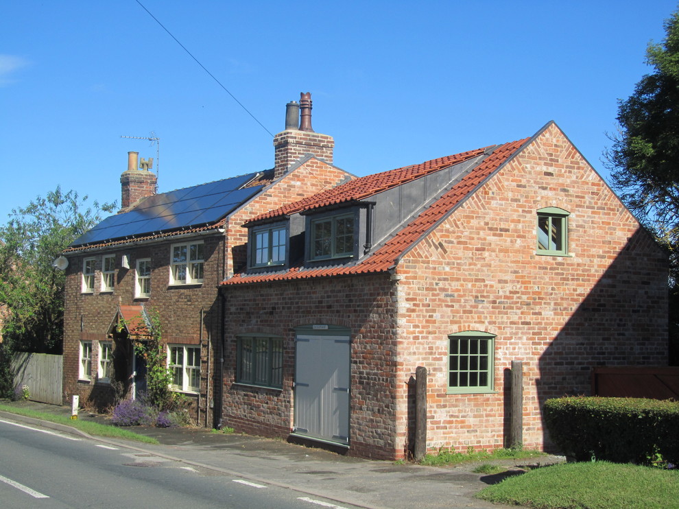 Large country two-storey brick red exterior in Other with a gable roof.