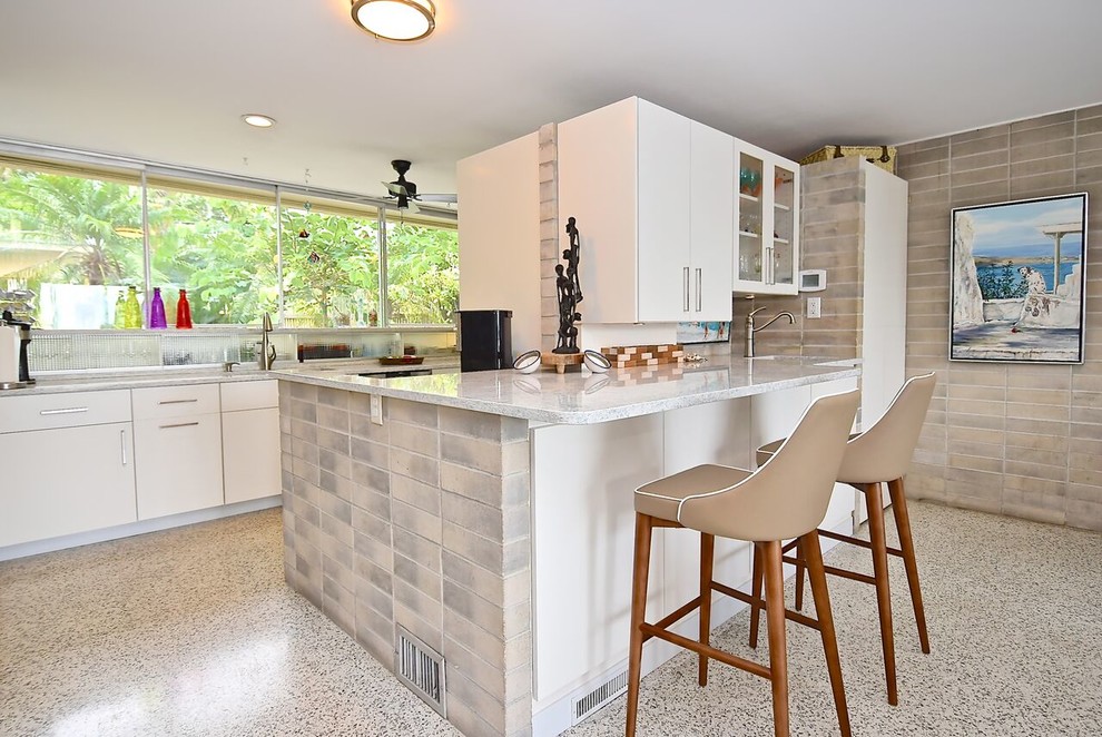 Design ideas for a large midcentury galley open plan kitchen in Other with an integrated sink, flat-panel cabinets, white cabinets, quartz benchtops, grey splashback, stainless steel appliances, terrazzo floors, with island, white floor and white benchtop.