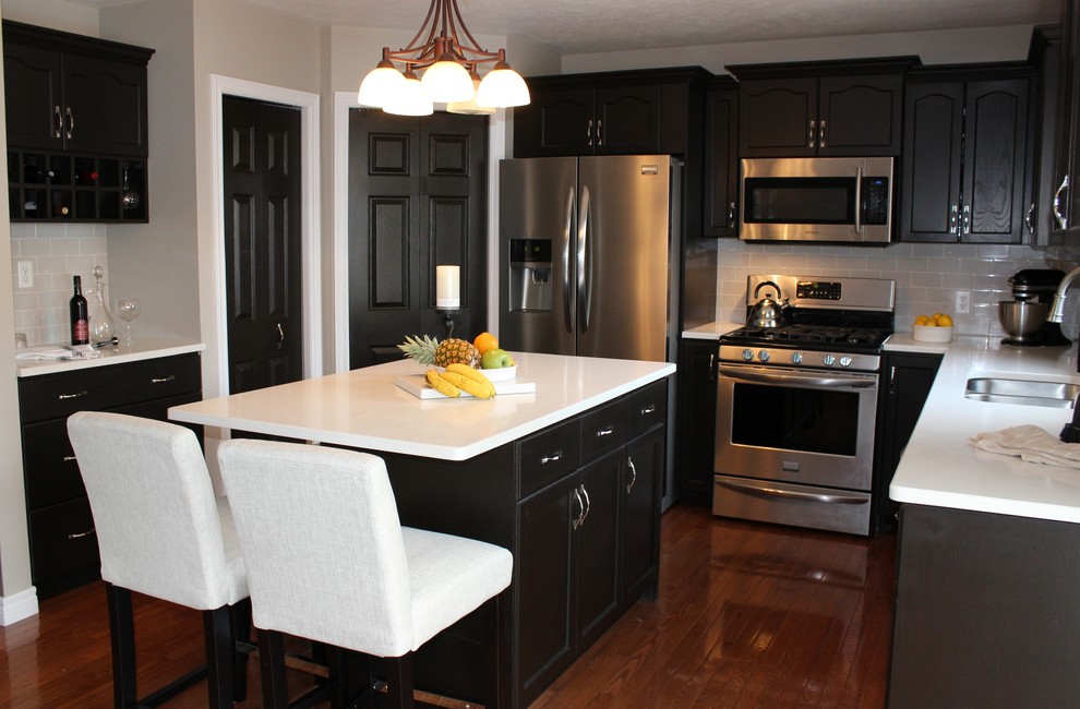 Example of a mid-sized transitional u-shaped medium tone wood floor open concept kitchen design in Toronto with an undermount sink, recessed-panel cabinets, dark wood cabinets, quartzite countertops, gray backsplash, subway tile backsplash, stainless steel appliances and an island