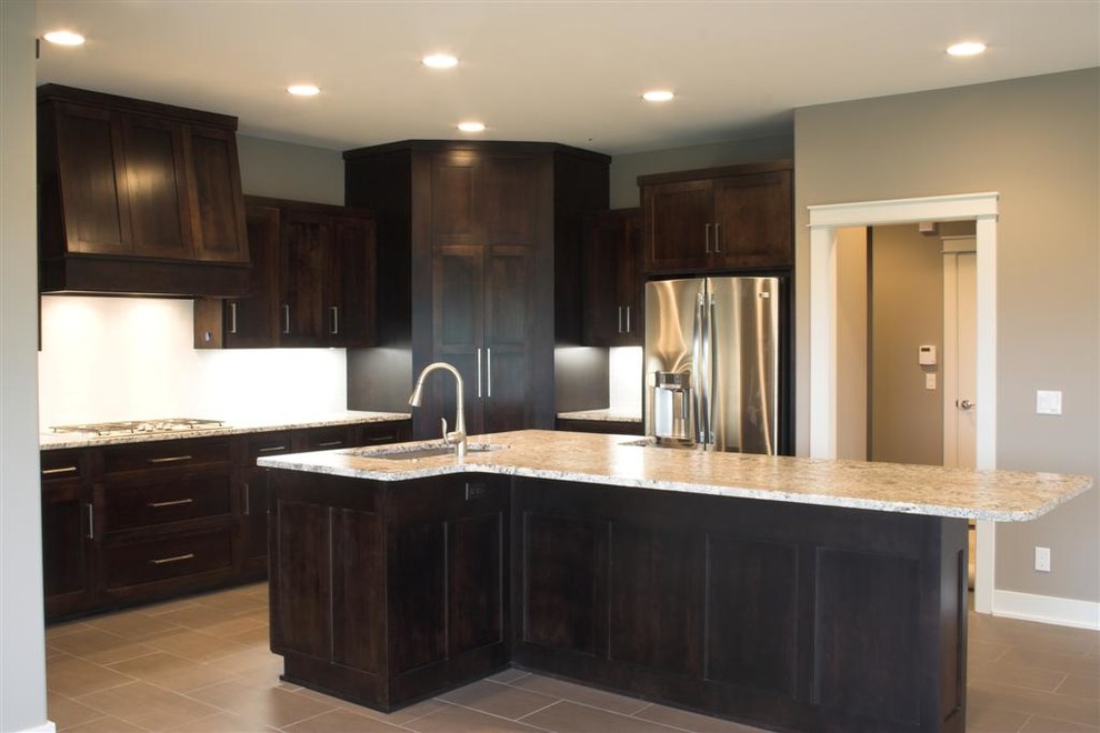 Photo of a transitional u-shaped eat-in kitchen in Omaha with an undermount sink, shaker cabinets, dark wood cabinets, granite benchtops, white splashback, stainless steel appliances and with island.