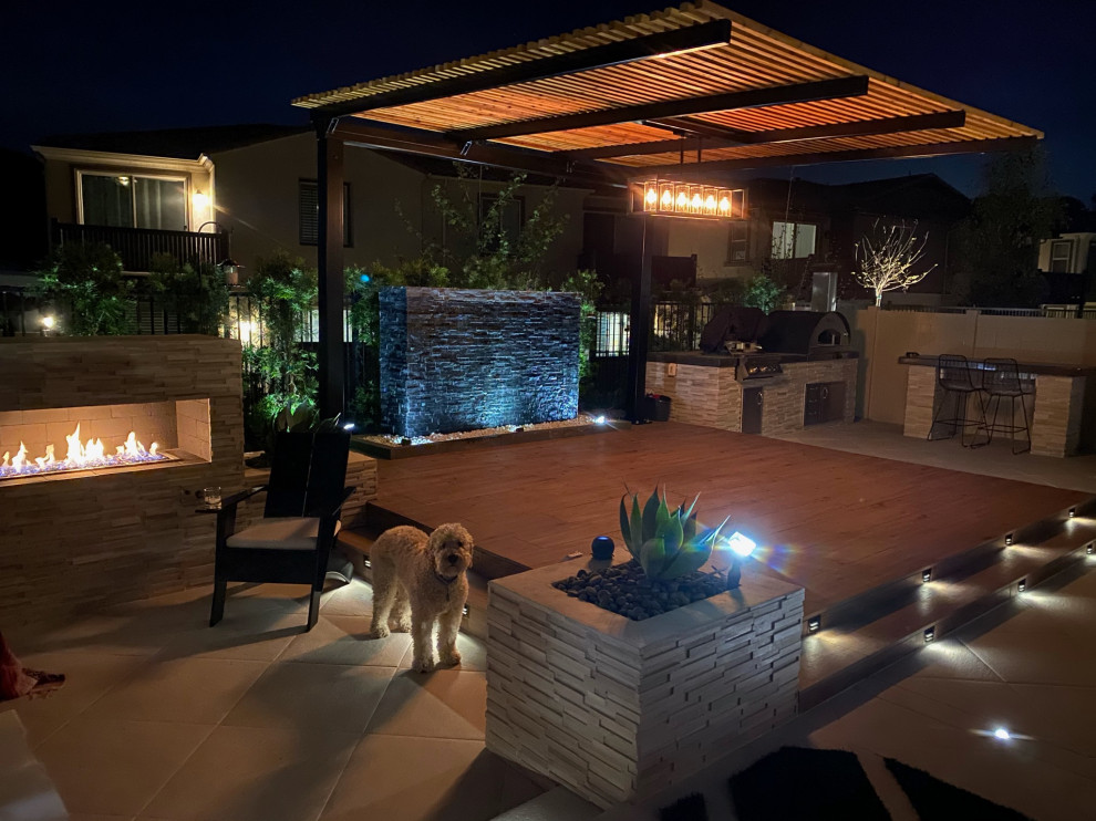 Design ideas for a mid-sized contemporary backyard full sun garden for summer in San Diego with a fire feature, concrete pavers and a vinyl fence.