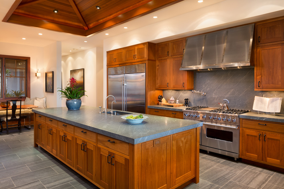 Tropical galley eat-in kitchen in Hawaii with an undermount sink, shaker cabinets, medium wood cabinets, grey splashback, stone slab splashback, stainless steel appliances and with island.