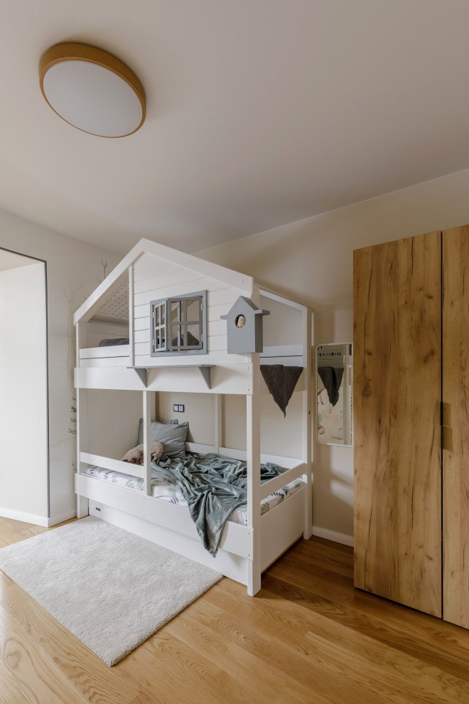 Photo of a large contemporary gender-neutral kids' playroom for kids 4-10 years old in Other with white walls, medium hardwood floors and brown floor.