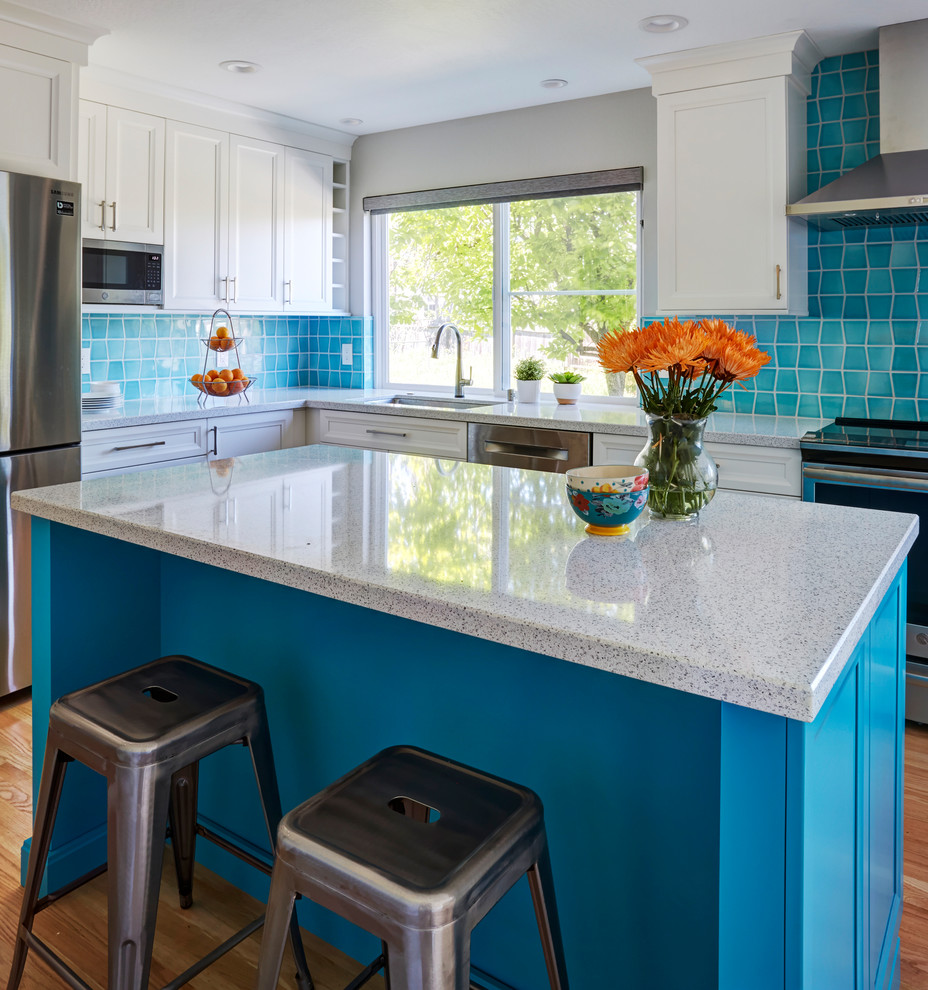 Inspiration for a mid-sized transitional u-shaped eat-in kitchen in San Francisco with an undermount sink, recessed-panel cabinets, blue cabinets, blue splashback, stainless steel appliances, medium hardwood floors, with island, brown floor and white benchtop.