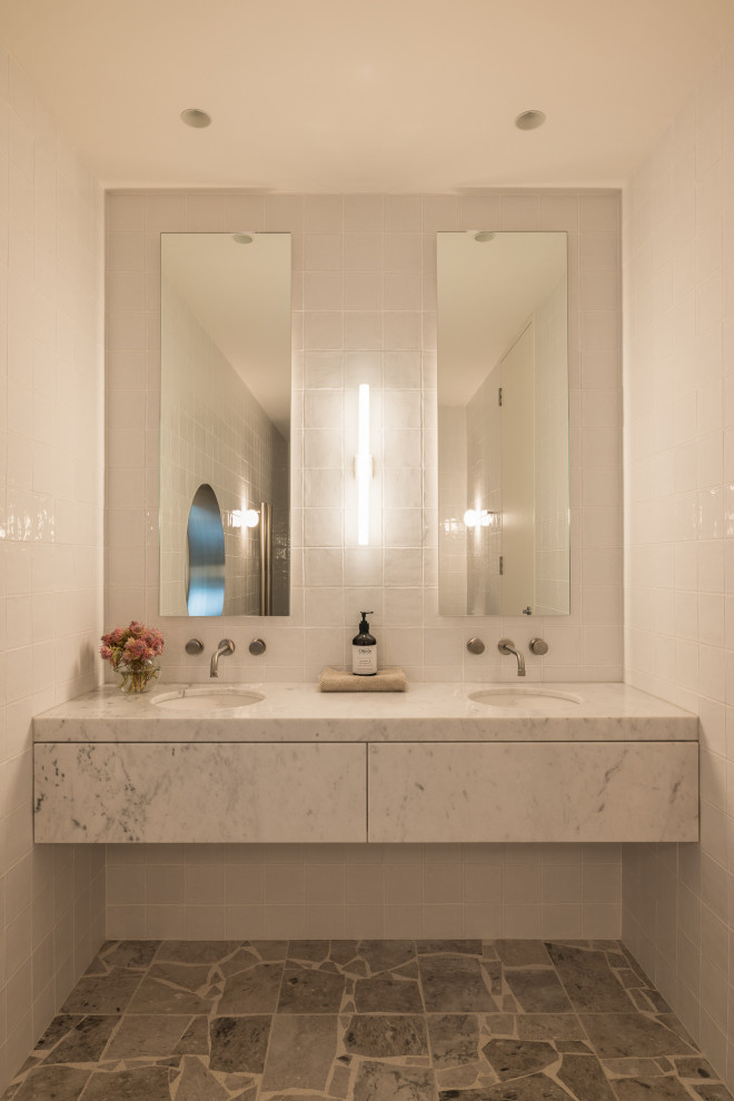На фото: ванная комната в стиле фьюжн с белой плиткой, керамической плиткой, белыми стенами, врезной раковиной, мраморной столешницей, серой столешницей, тумбой под две раковины и подвесной тумбой с