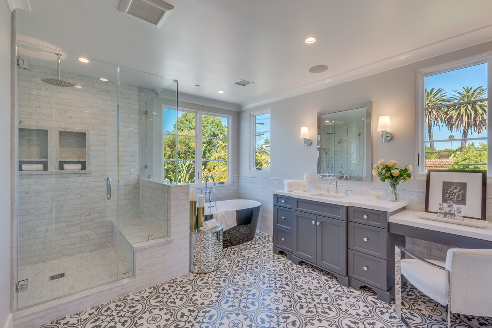 This is an example of a transitional 3/4 bathroom in Los Angeles with shaker cabinets, grey cabinets, a corner shower, white tile, grey walls, an undermount sink, white floor and a hinged shower door.