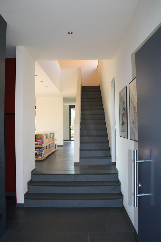 Photo of a mid-sized contemporary foyer in Other with white walls, limestone floors, a single front door and a gray front door.