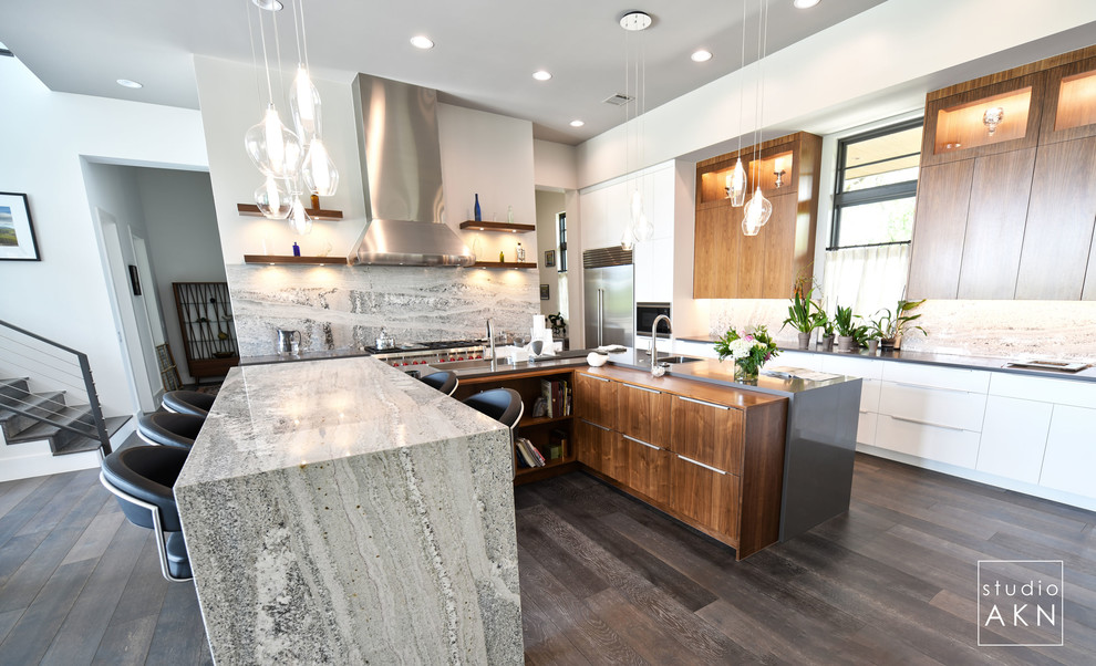 This is an example of a large modern u-shaped eat-in kitchen in Austin with flat-panel cabinets, medium wood cabinets, quartzite benchtops, grey splashback, marble splashback, stainless steel appliances, with island, brown floor and grey benchtop.
