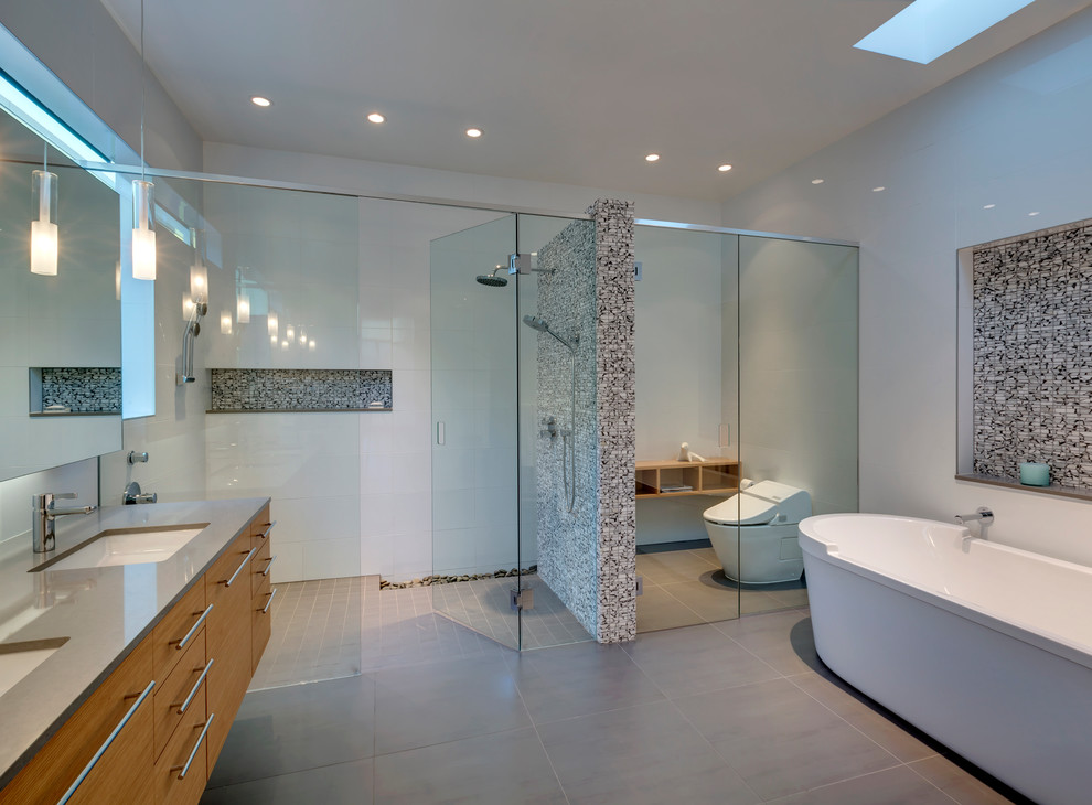 Photo of a large modern master bathroom in Dallas with an undermount sink, furniture-like cabinets, medium wood cabinets, engineered quartz benchtops, a freestanding tub, a curbless shower, a one-piece toilet, white tile, ceramic tile, white walls and porcelain floors.