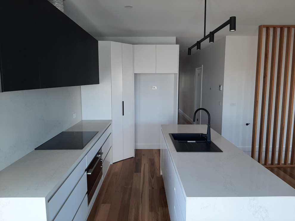 Inspiration for a modern l-shaped open plan kitchen in Melbourne with white cabinets, engineered stone countertops, white splashback, engineered quartz splashback, an island and white worktops.