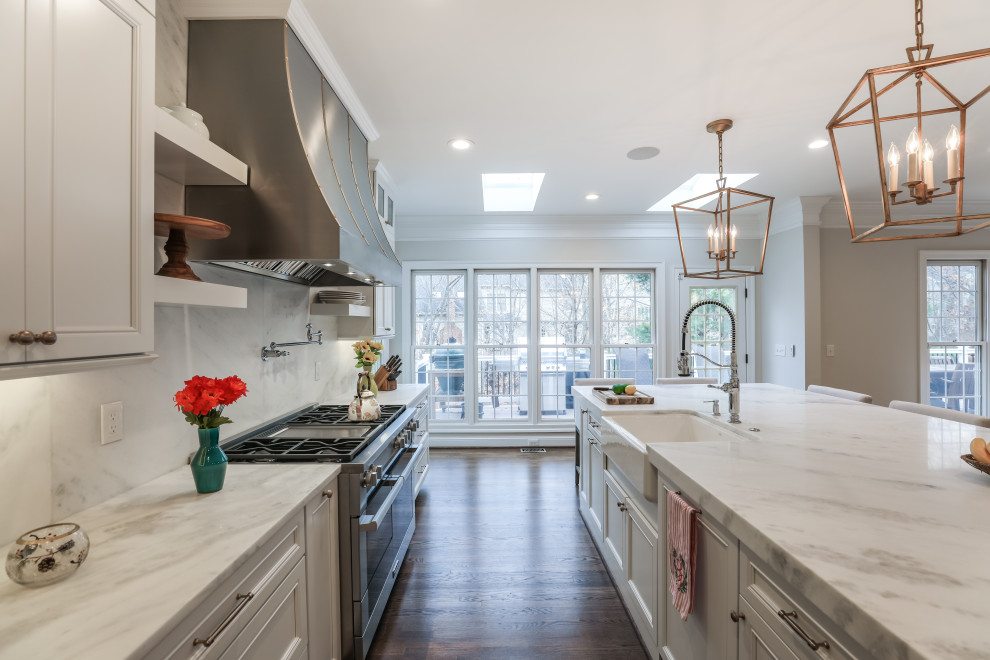 Mid-sized contemporary eat-in kitchen in DC Metro with a farmhouse sink, recessed-panel cabinets, white cabinets, granite benchtops, white splashback, engineered quartz splashback, stainless steel appliances, medium hardwood floors, with island, brown floor and white benchtop.
