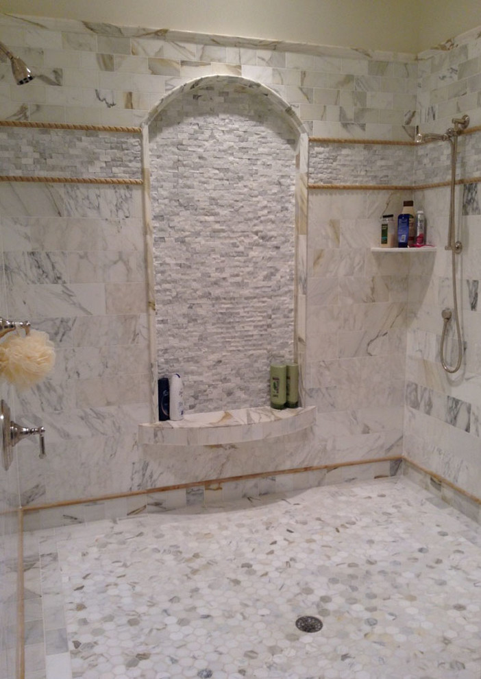 This is an example of a large contemporary master bathroom in Cleveland with marble floors, a double shower and white tile.