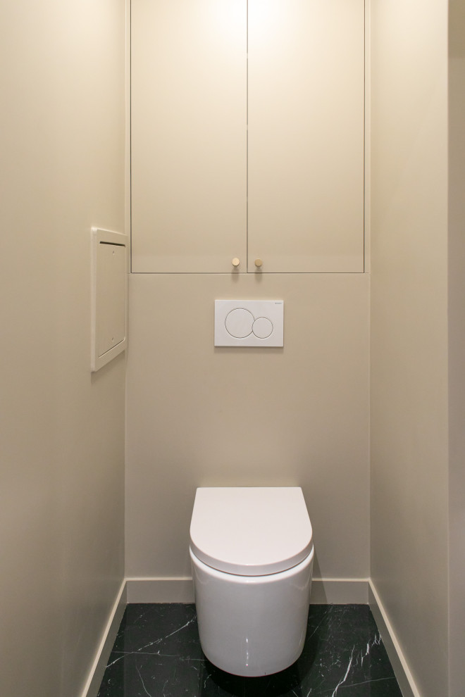 Small modern powder room in Le Havre with recessed-panel cabinets, beige cabinets, a wall-mount toilet, black and white tile, beige walls, marble floors and a built-in vanity.