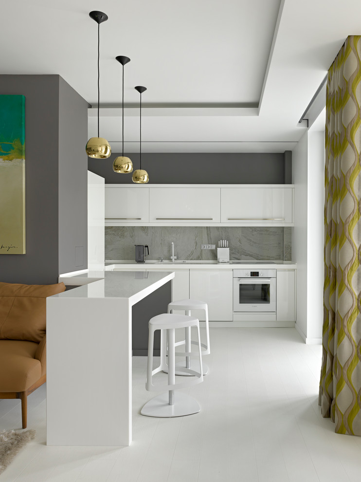 Photo of a contemporary kitchen in Moscow with flat-panel cabinets, white cabinets, grey splashback, white appliances, a peninsula, porcelain splashback, painted wood floors, white floor and white benchtop.